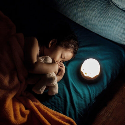 a small girl sleeping beside the night light